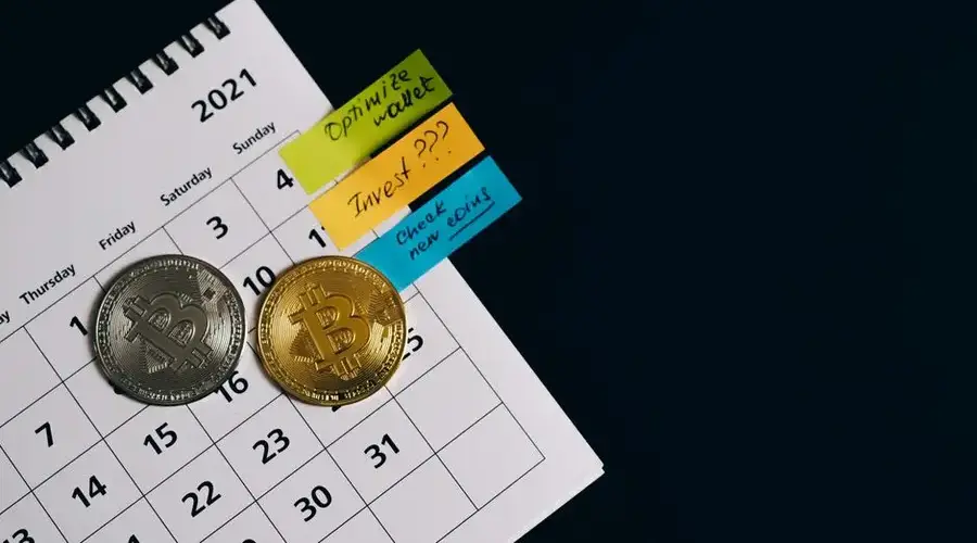 Close-up of Bitcoins on a calendar highlighting investment plans with sticky notes.