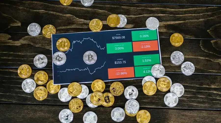 Bitcoin coins scattered around a stock chart on a dark wooden table, symbolizing cryptocurrency investment.
