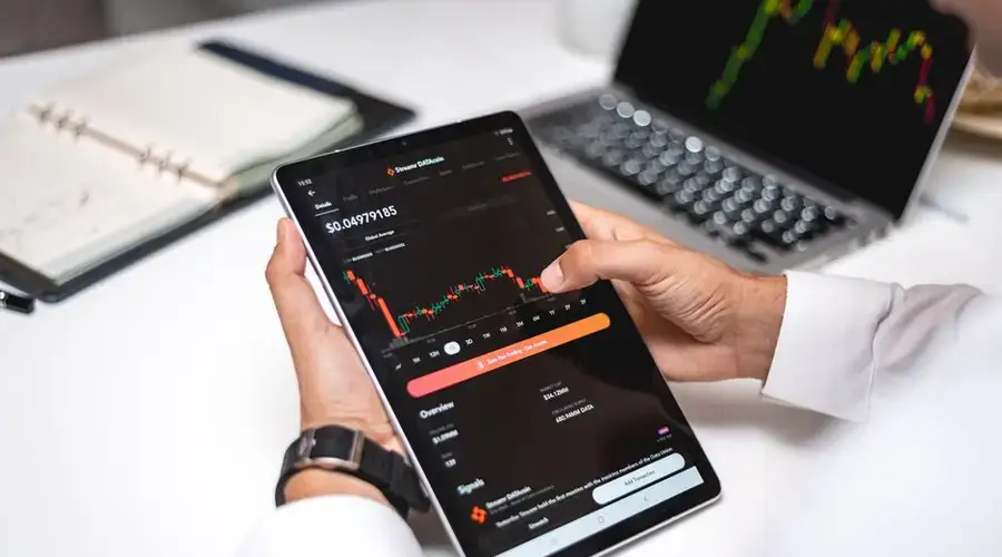 Professional analyzing cryptocurrency market data on a digital tablet with financial graphs.