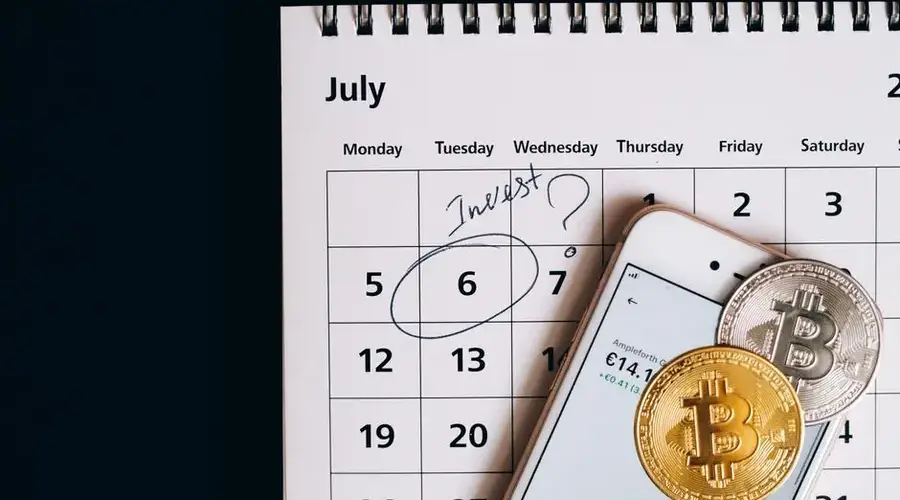 Smartphone with bitcoins on calendar, marking investment date.