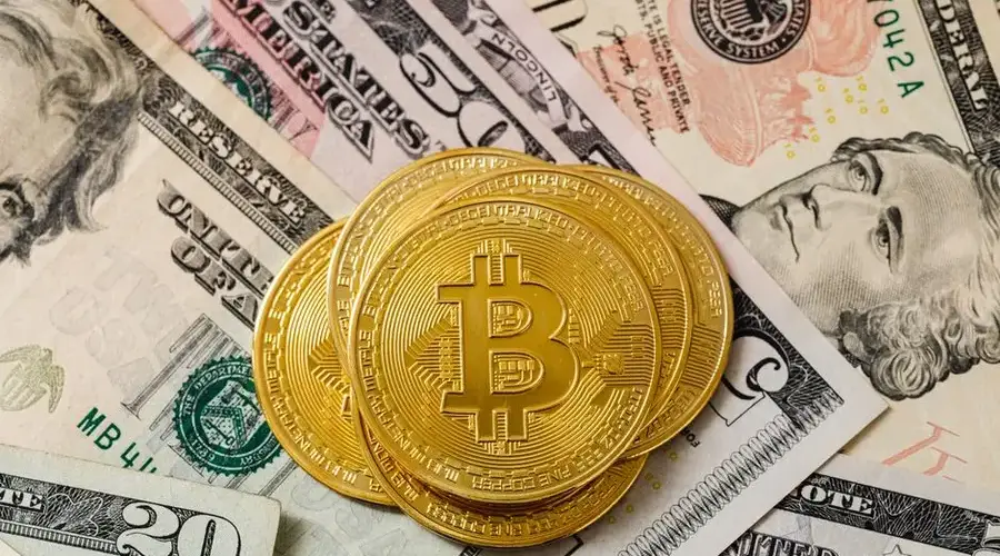 Close-up of gold bitcoin coins on US paper money, representing cryptocurrency investment.