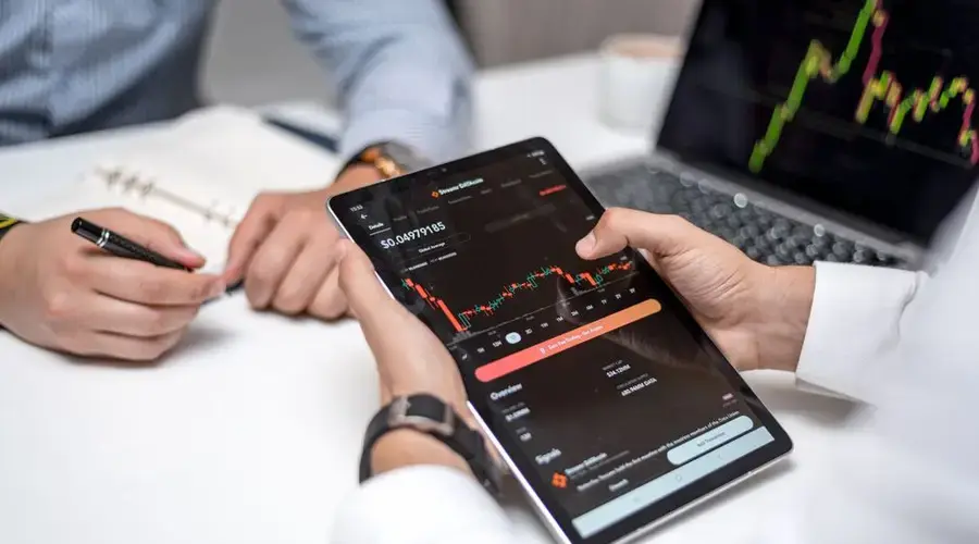 Professionals analyzing cryptocurrency data on a digital tablet during a business meeting.
