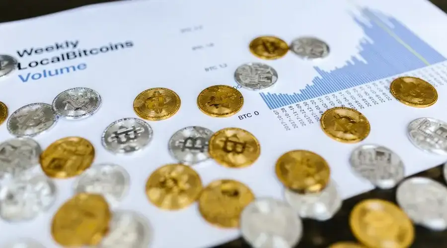 Gold and silver Bitcoin coins placed on a graph showing LocalBitcoins trading volume analysis, symbolizing cryptocurrency market trends.