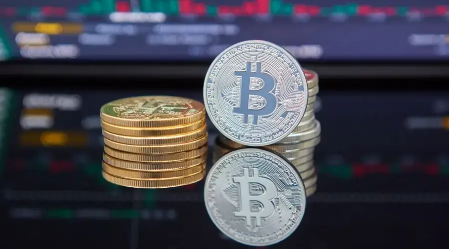 Bitcoin coins stacked in front of cryptocurrency trading chart reflecting market trends.
