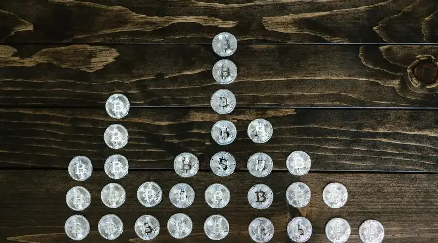 Silver bitcoin coins organized on a dark wooden table forming a visual pattern symbolizing cryptocurrency growth.