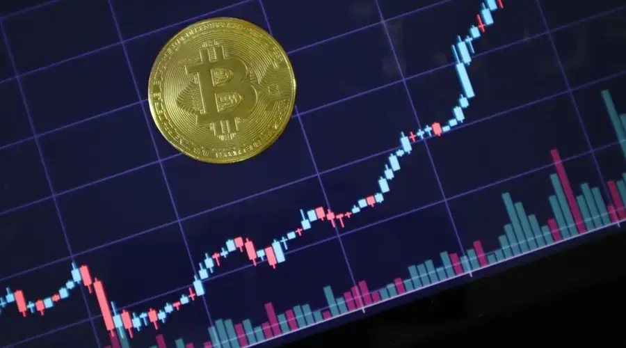 Gold Bitcoin on screen with rising investment chart indicating cryptocurrency growth.