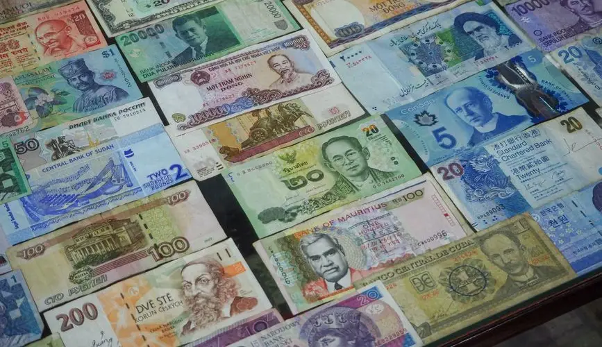 From above collection of various colorful banknotes from different countries arranged in row on table