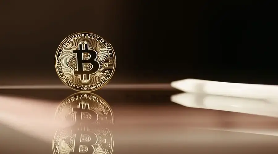 A close-up image of a Bitcoin coin reflecting on a shiny surface, highlighting cryptocurrency themes.