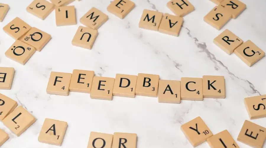 Wooden Scrabble tiles arranged to spell 'Feedback' on a marble background.