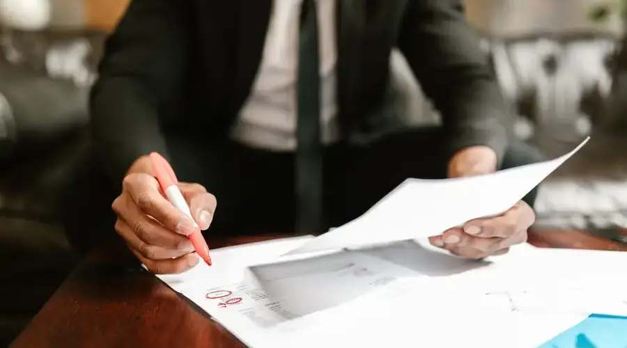 Businessman working with financial documents at office desk, highlighting details.