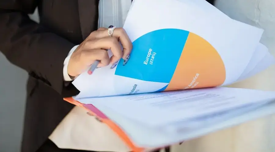 Close-up of a businesswoman reviewing financial documents with a colorful pie chart.