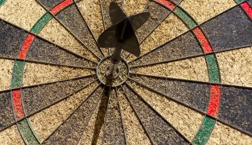 Dart perfectly hitting the bullseye on a dartboard, showcasing precision and success.