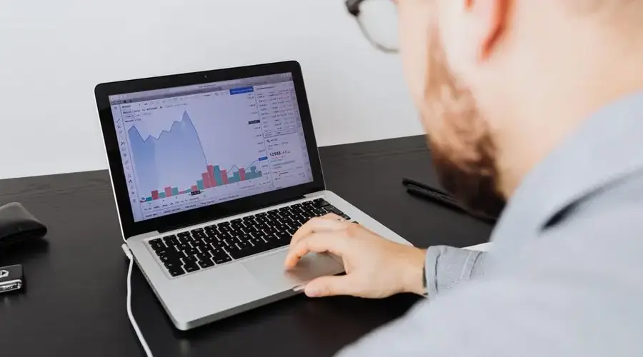 Man working on a laptop analyzing business data and financial graphs indoors.