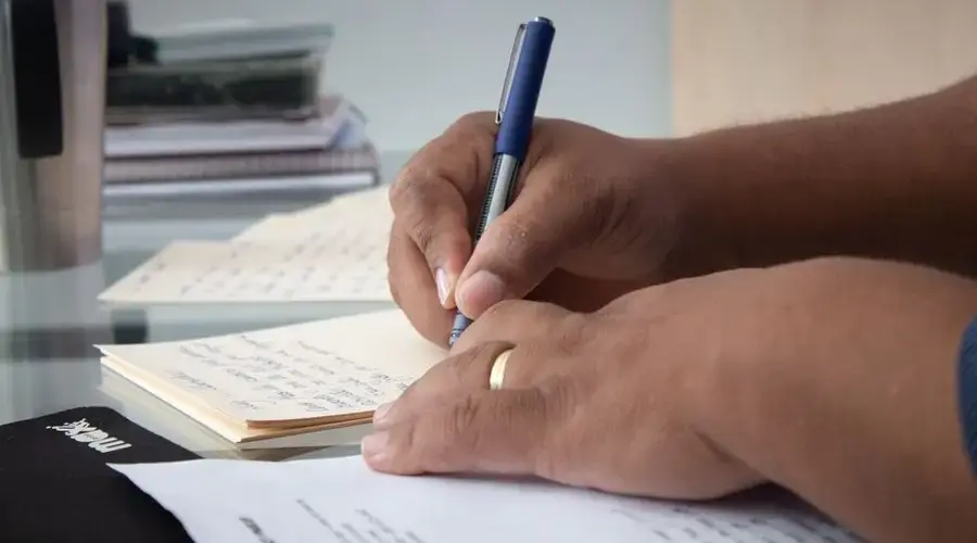 Close-up of hands with a pen writing notes on paper, suited for education or business themes.