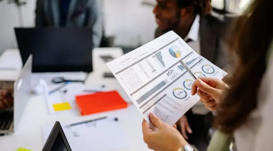 Professionals reviewing business charts and documents in a team meeting.