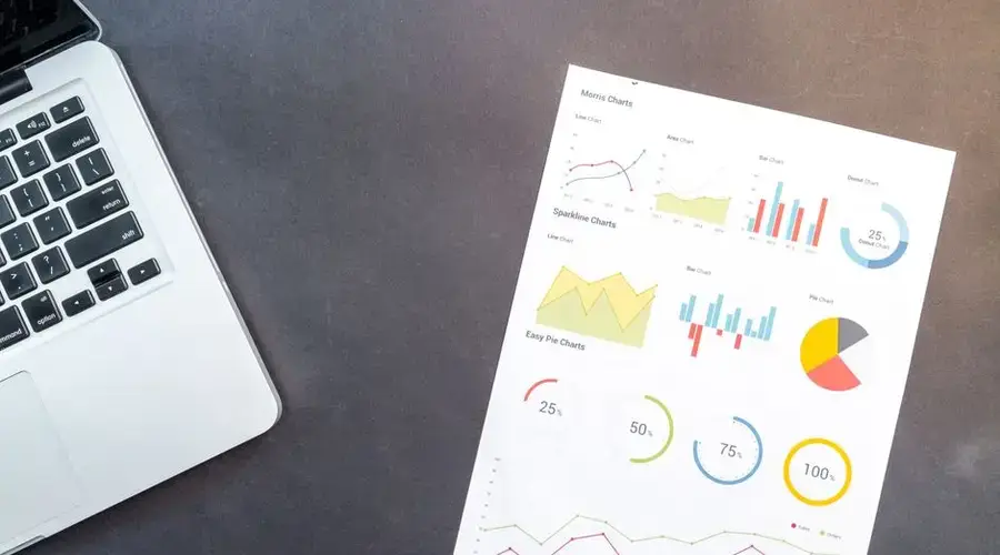 Modern desk setup with a laptop and analytical charts showcasing data interpretation and business analysis.