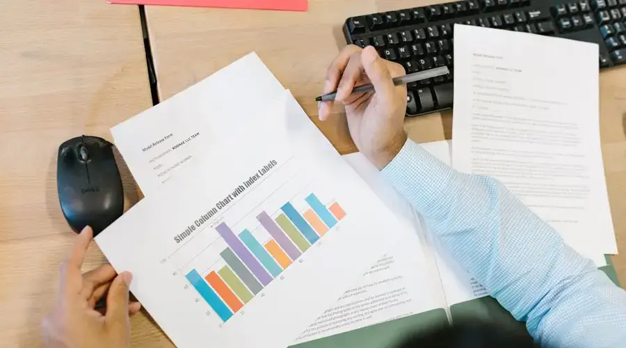 A business analyst reviews a colorful bar chart and documents at a desk, indicating data analysis.