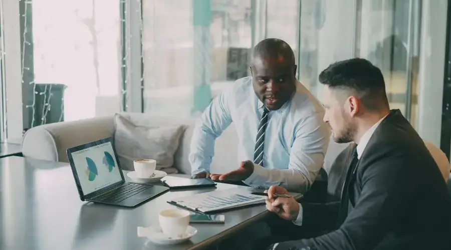 Two businessmen discussing data at a cafe while enjoying coffee.