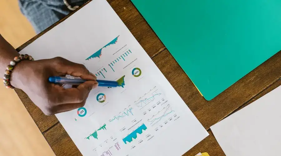 Overhead view of a person analyzing business charts and graphs on paper.