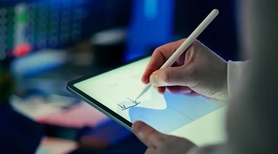 Business person using a stylus to analyze data on a digital tablet in an office setting.