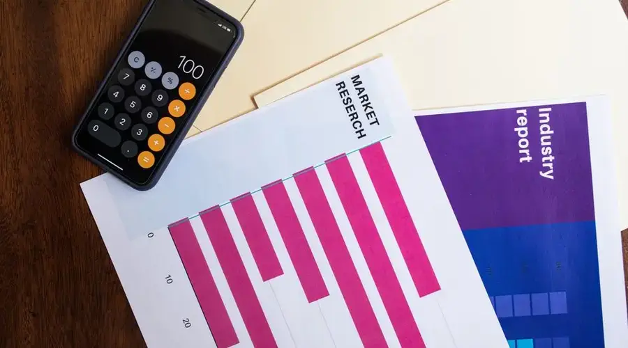 Flat lay of smartphone and market research papers on wooden table for business analysis.
