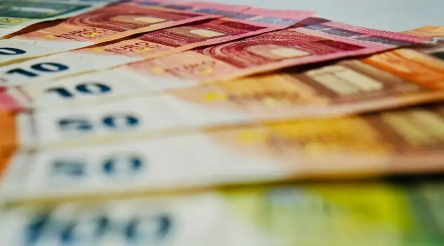 A close-up image of euro banknotes in various denominations spread out, showcasing currency details.