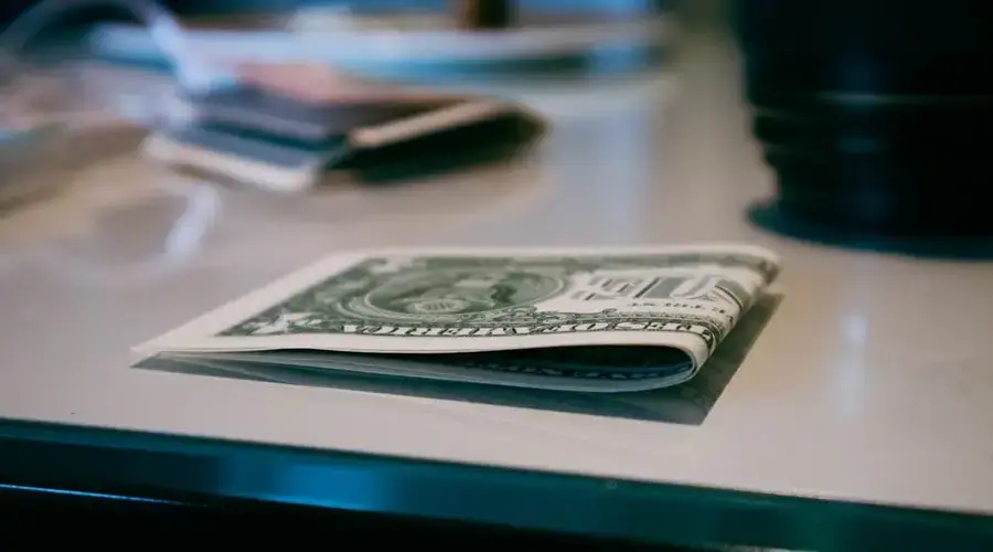 Detailed shot of a folded US dollar note on a reflective surface indoors.