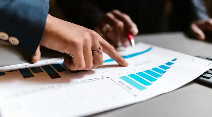 Close-up of hands analyzing financial charts during a business meeting.