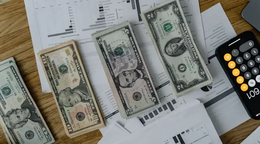 A workspace setup featuring cash, documents, and a calculator symbolizing financial analysis and budgeting.
