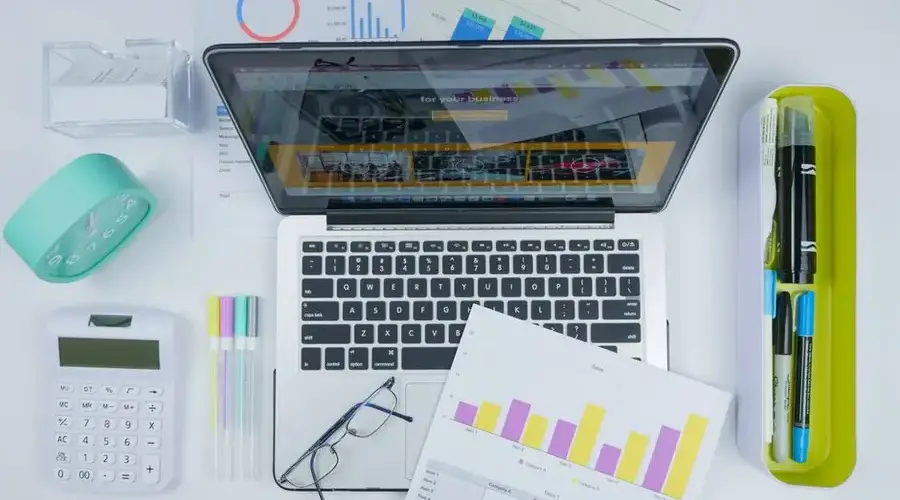Top view of a creative workspace featuring a laptop, charts, and office stationery.