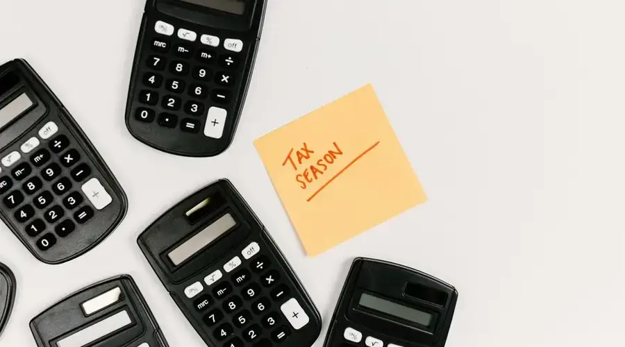 Top view of calculators with a tax season sticky note on a white background.