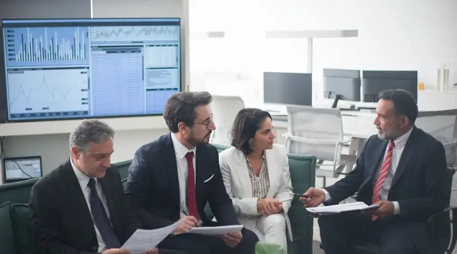 Group of business professionals discussing financial strategies in a modern office setting.