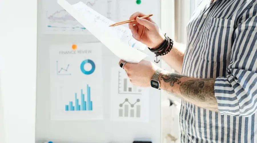 Professional reviewing financial graphs and documents in a bright office setting.