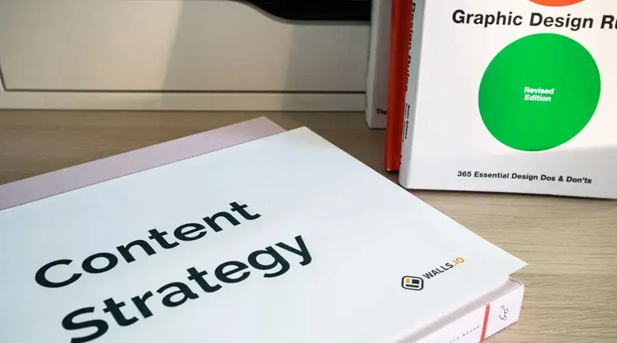 Books on content strategy and graphic design essentials resting on a wooden desk.