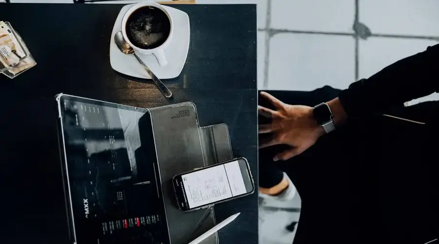 Overhead shot of a modern workspace with coffee, tablet, and smartphone, emphasizing technology usage.