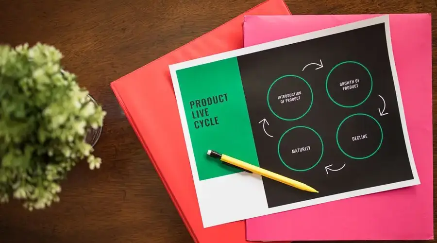 Flat lay of a product lifecycle illustration with a pencil and folders, ideal for business presentations.