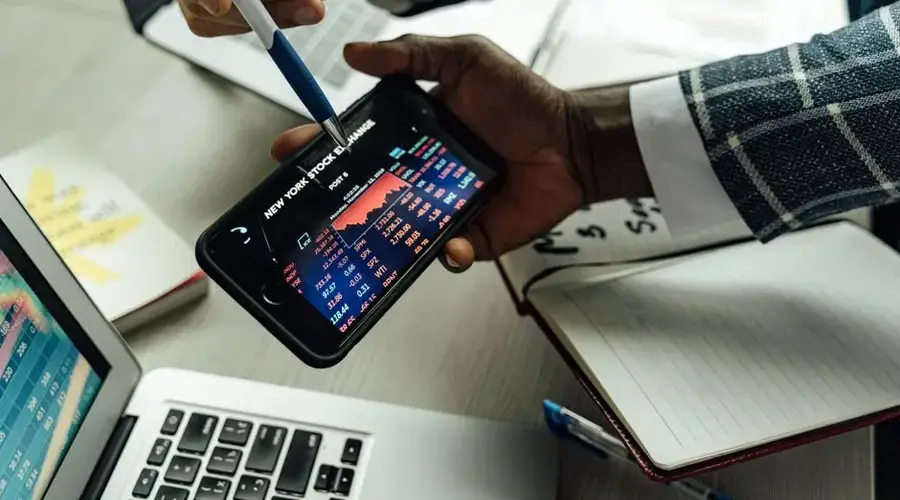Business professionals analyzing stock exchange data on a smartphone in an office setting.