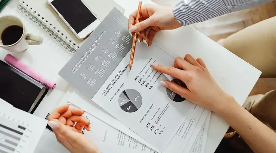 Team collaborating on financial documents with graphs and statistics in an office setting.
