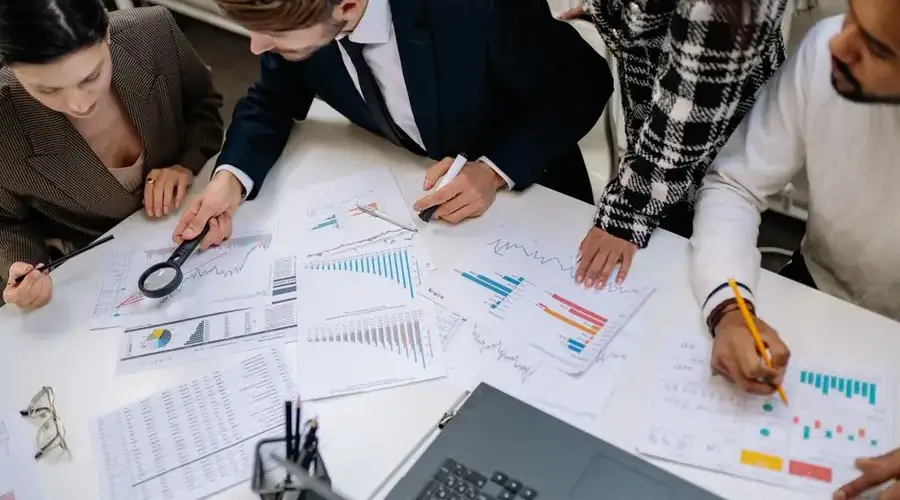 A group of professionals reviewing financial charts in an office meeting setting.