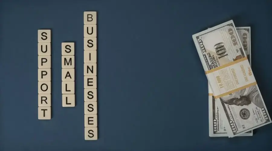 Conceptual image of supporting small businesses with financial resources using money and letter tiles.