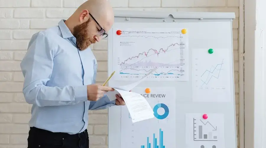 Business person in an office reviewing financial documents on a whiteboard.