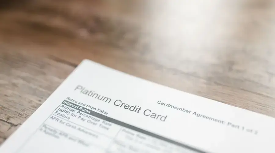 Close-up of a platinum credit card document with interest rates table on a wooden surface.