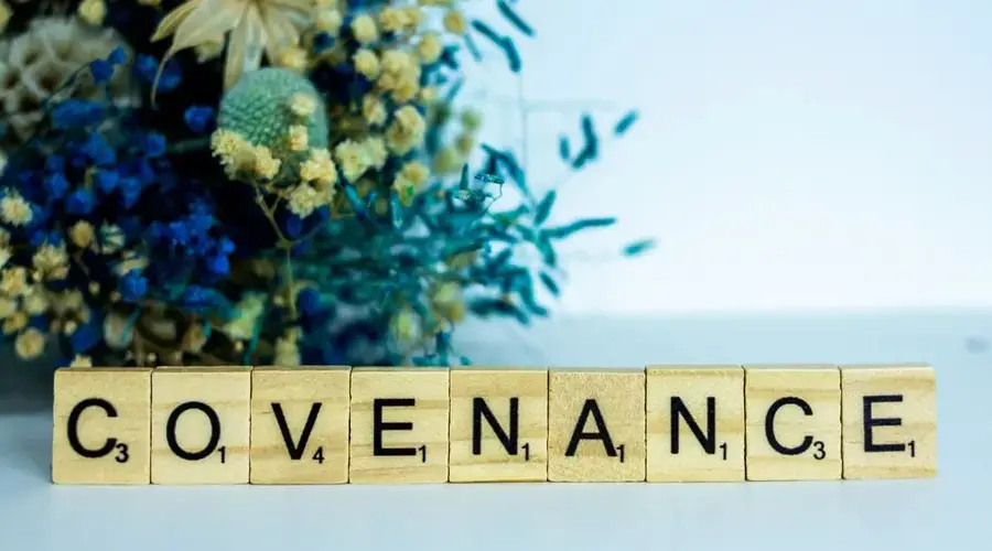 Wooden Scrabble tiles spelling 'Covenance' with a floral backdrop, offering creative inspiration.