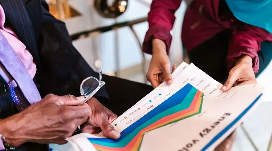 Two professionals reviewing detailed energy consumption charts in an office setting.