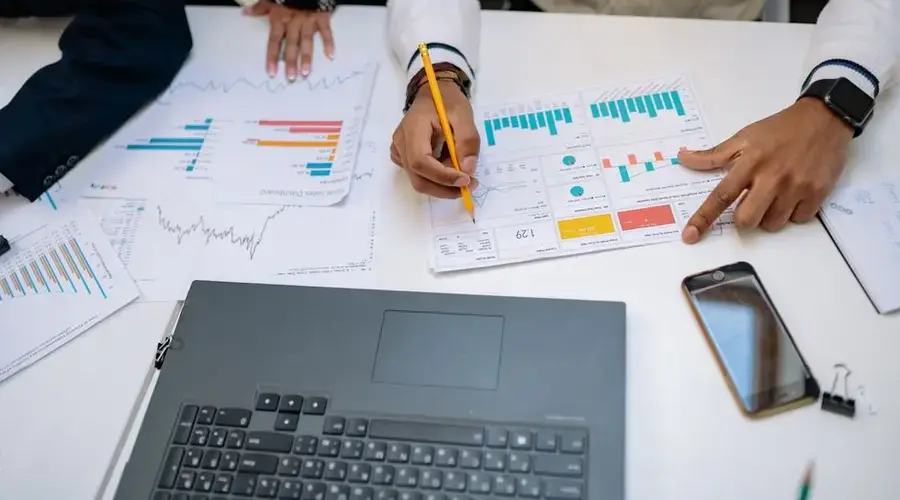Team of professionals working on financial reports using charts and devices.