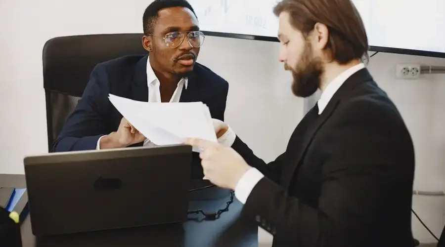 Professionals examining documents in an office business meeting setup.