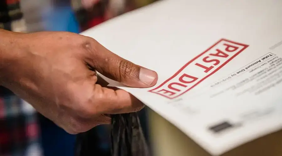 A close-up of a hand holding a document with a 'Past Due' stamp, highlighting financial urgency.