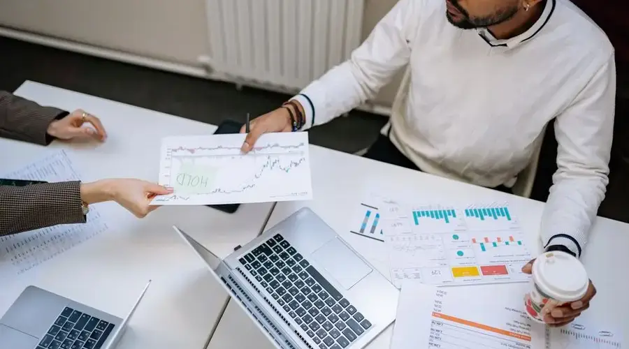 Colleagues collaborating on financial charts and data during a business meeting indoors.