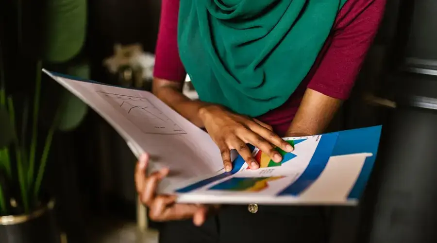 Close-up of a person reviewing charts and reports in an office setting.