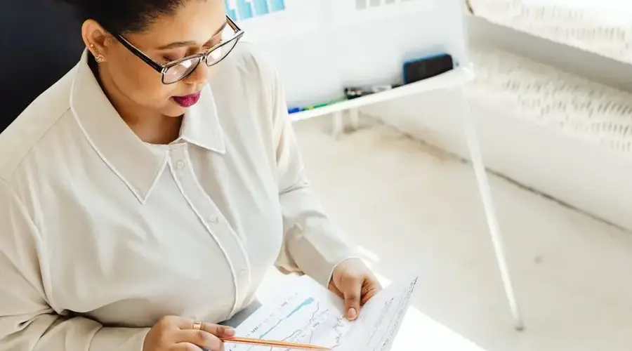African American woman analyzing financial charts indoors with focus on market trends.